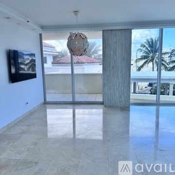 Miami Beach apartment for rent - A modern living room with a television and a hanging light fixture.