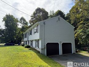 Simsbury house for rent - A two-story house with a garage is surrounded by greenery.