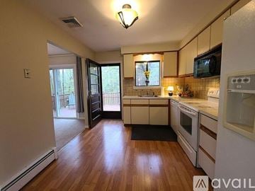 Simsbury house for rent - A kitchen with white cabinets and a black mat on the floor.