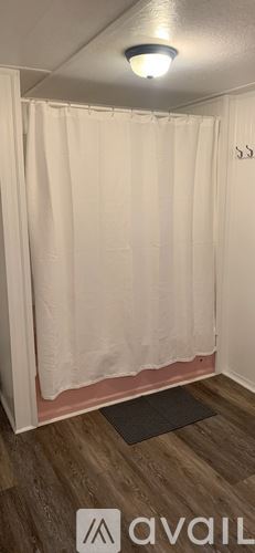 Calais apartment for rent - A bathroom with a white shower curtain and wooden flooring.