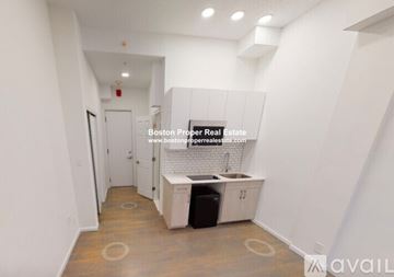 Boston apartment for rent - A kitchen area with a sink and cabinets in a white room.