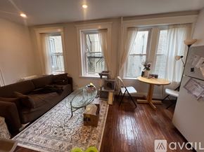 Boston apartment for rent - A living room with a brown couch, a glass coffee table, and a white refrigerator.
