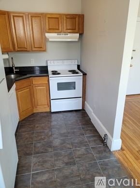 Boston apartment for rent - A kitchen with wooden cabinets and a white stove top oven.