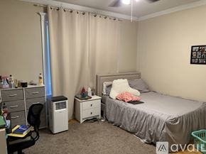 Boston apartment for rent - A bedroom with a bed, desk, chair, and window with curtains.