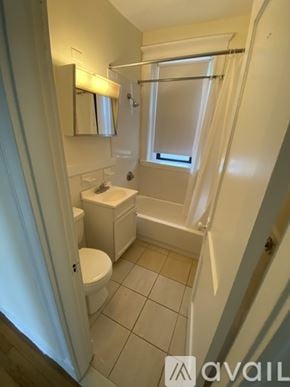 Boston apartment for rent - A small white bathroom with a toilet, sink, and bathtub.