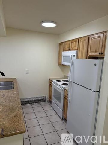 Boulder condo for rent - A kitchen with a white refrigerator, a microwave above the stove, and wooden cabinets.