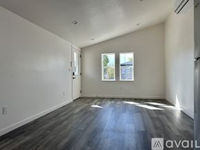 Denver house for rent - A spacious room with wooden flooring and a window showing a view of a building outside.
