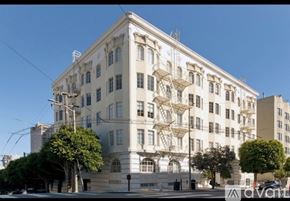 San Francisco condo for rent - A large white building with many windows and balconies is surrounded by trees and has a clear blue sky above it.