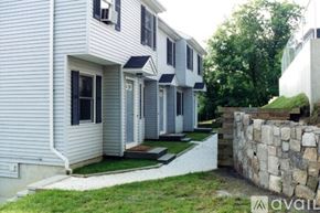 Danbury apartment for rent - A white house with a stone wall in front.
