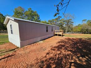 Norman house for rent - A small white building with a brown roof is situated on a dirt area.