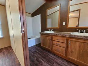 Norman house for rent - A bathroom with a brown wooden vanity and a white bathtub.
