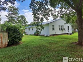 Warrenton apartment for rent - A white house with a green lawn and trees in the background.