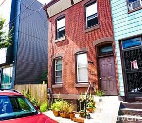 Philadelphia apartment for rent - A red car is parked in front of a red brick house.