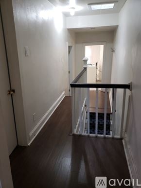 Philadelphia apartment for rent - A hallway with a black railing and wooden floors.