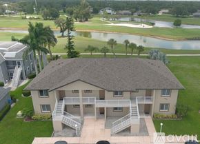 Port Charlotte apartment for rent - A house with a roof and a balcony is in the foreground of a golf course.