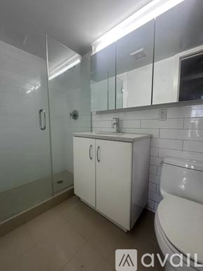 New York apartment for rent - A white bathroom with a glass shower door and a white toilet.