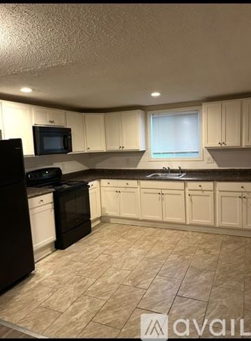 Derby apartment for rent - A kitchen with black appliances and white cabinets.