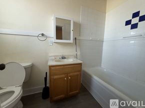Raton apartment for rent - A bathroom with a toilet, sink, and a wooden cabinet.