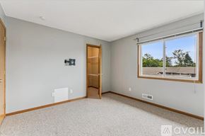 Eagan apartment for rent - A room with a carpeted floor, a window with a view of trees, and a door leading to another room.