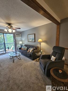 Taunton condo for rent - A living room with a black couch, a black chair, a glass table, and a ceiling fan.