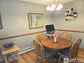 Taunton condo for rent - A dining room with a round wooden table surrounded by chairs.