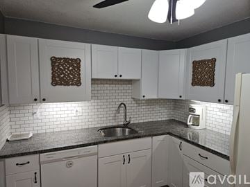 Taunton condo for rent - A kitchen with white cabinets and a black countertop.