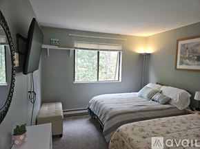 Taunton condo for rent - A bedroom with a bed, a bench, and a television.