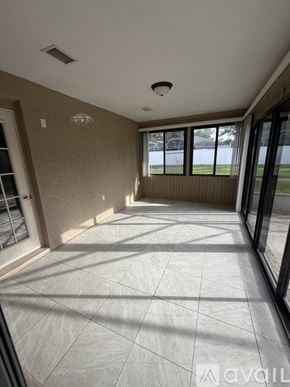 Palm Coast house for rent - A room with a tiled floor and a window showing a view of a fence and trees.