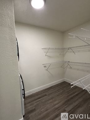 Miami apartment for rent - A room with a white wall and a wooden floor with a clothes rack.