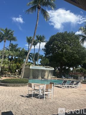 Miami apartment for rent - A pool surrounded by palm trees and lounge chairs.