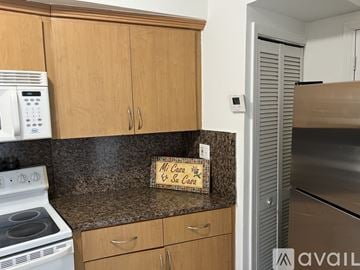 Miami apartment for rent - A kitchen with wooden cabinets and a white stove top oven.