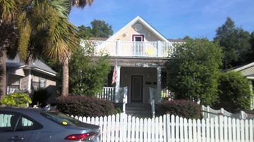 Pensacola apartment for rent - A house with a white picket fence and a car parked in front.