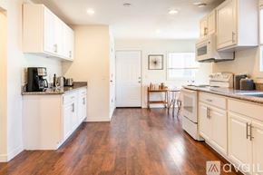 Portland house for rent - A kitchen with white cabinets and a wooden floor.