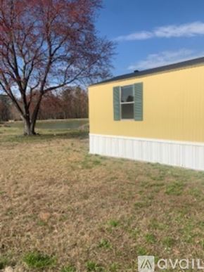 Zebulon apartment for rent - A yellow house with a white fence and a tree with red leaves in the background.