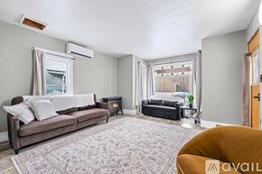 Sturgis apartment for rent - A two-story house with a white exterior and a black roof is situated on a street with a tree to the right.