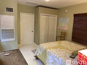 Miami apartment for rent - A bedroom with a bed, a chair, and a window with blinds.