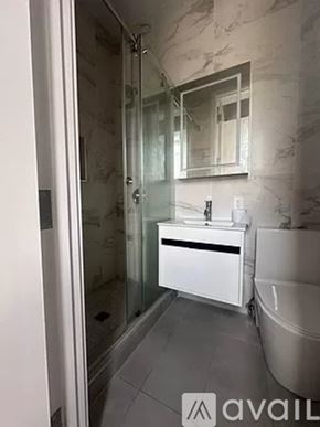 New York apartment for rent - A bathroom with a sink, mirror, and glass shower door.
