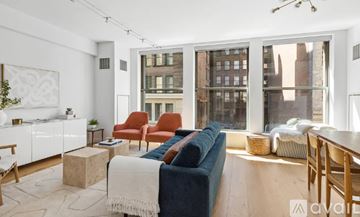 New York apartment for rent - A living room with a blue couch and a large window.