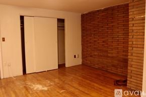 Boston apartment for rent - A room with a wooden floor and a brick wall.