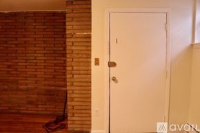 Boston apartment for rent - A white door with a gold handle is in a room with a brick wall.