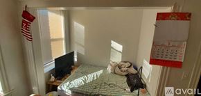 Boston apartment for rent - A bedroom with a bed, a TV, a window with blinds, and a calendar hanging on the wall.