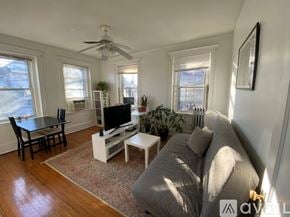 Boston apartment for rent - A living room with a grey couch, a black table, a television, and a ceiling fan.