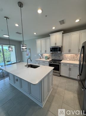 Naples condo for rent - A modern kitchen with white cabinets and a large island.