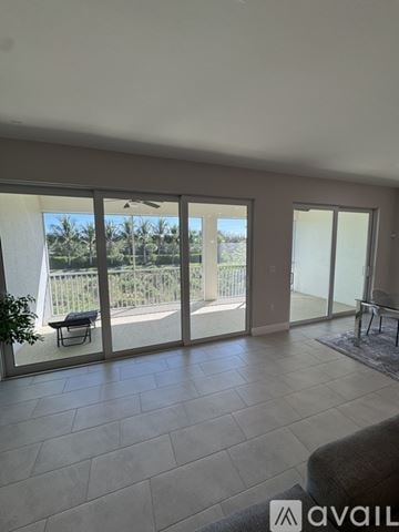 Naples condo for rent - A living room with a couch and a view of a fence and trees outside.