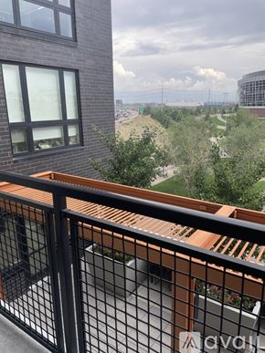 Denver apartment for rent - A balcony with a black railing and a view of a green landscape and buildings in the distance.