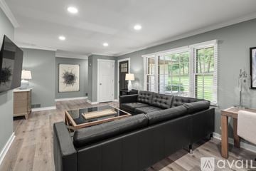 Asheville house for rent - A modern living room with a black leather sofa and wooden coffee table.