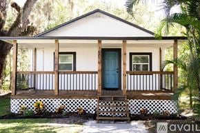 Sanford house for rent - A small white house with a blue door and a porch.