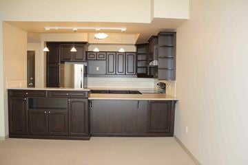 Winnipeg apartment for rent - A kitchen with dark wood cabinets and a stainless steel refrigerator.