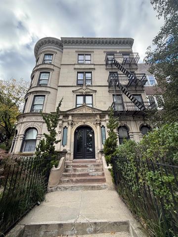 Brooklyn apartment for rent - A large, old building with a black door and a fire escape on the side.