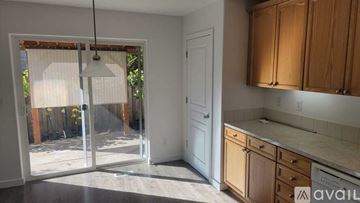 Beaverton house for rent - A kitchen with wooden cabinets and a sliding glass door leading to a backyard.